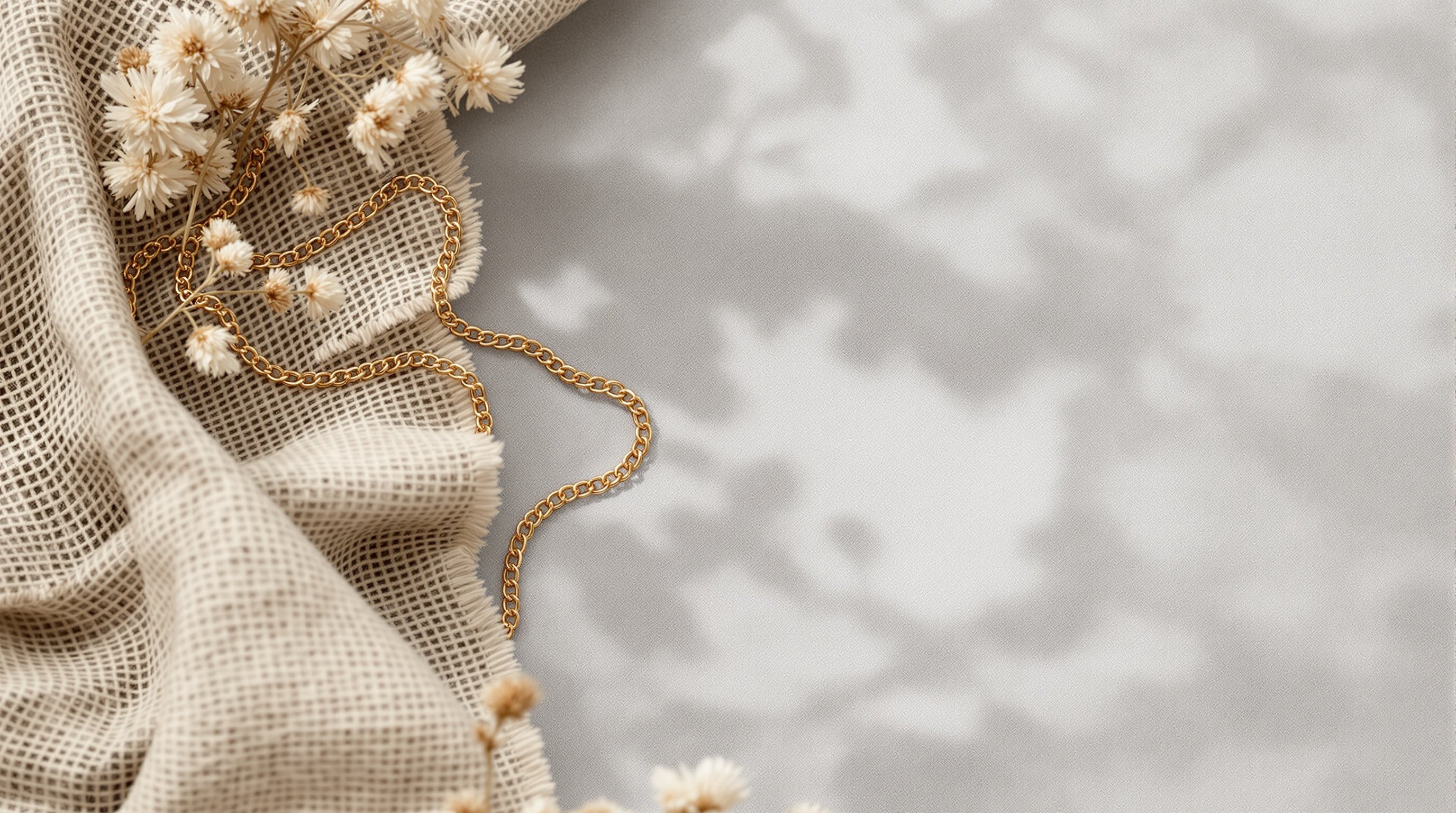 A gold anchor chain necklace draped over textured beige linen fabric.