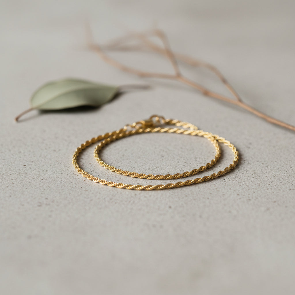 twisted gold bracelet on a minimalist stone surface.
