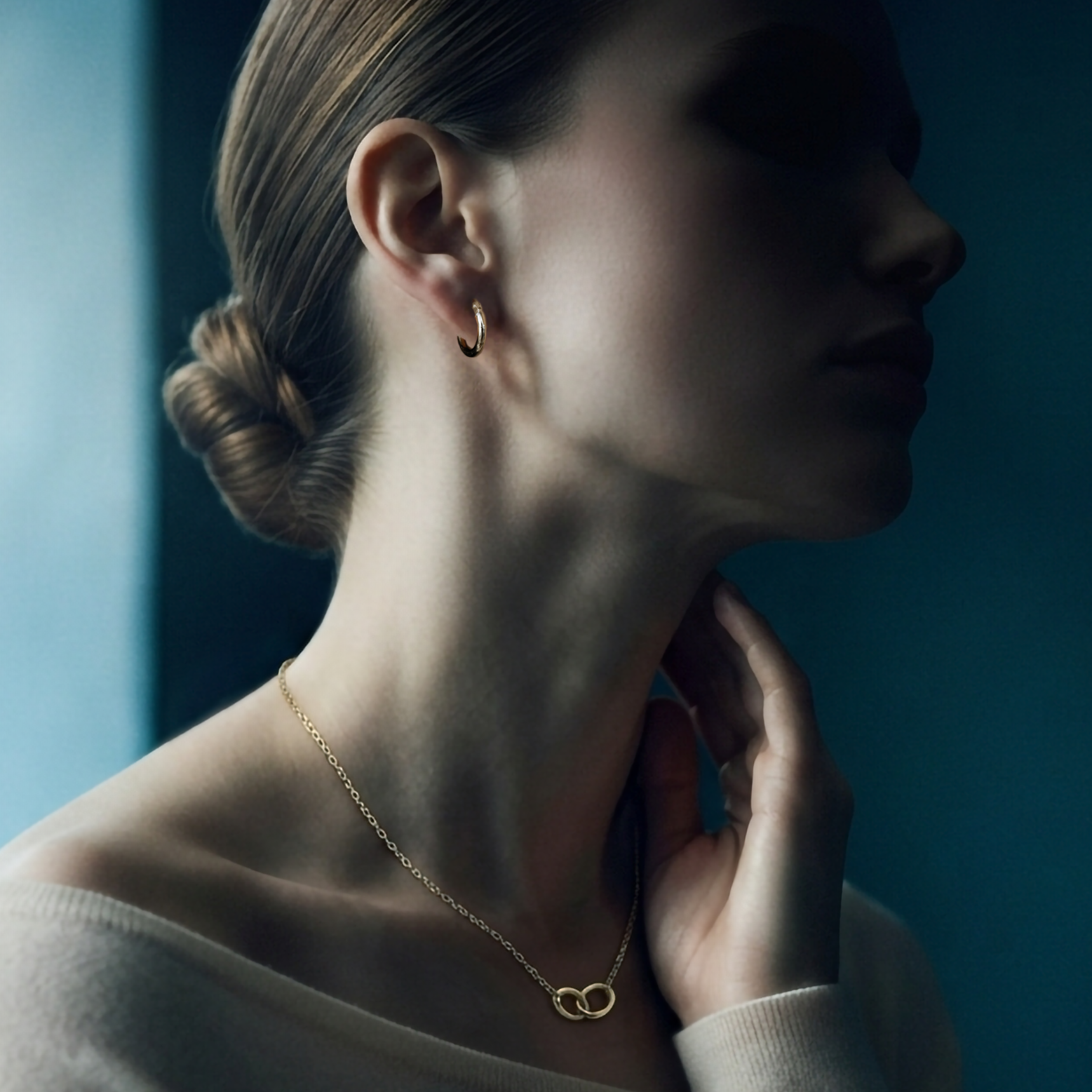 Woman in profile wearing a gold hoop earring and a thin gold necklace with interlocking rings from Nordic Bling.