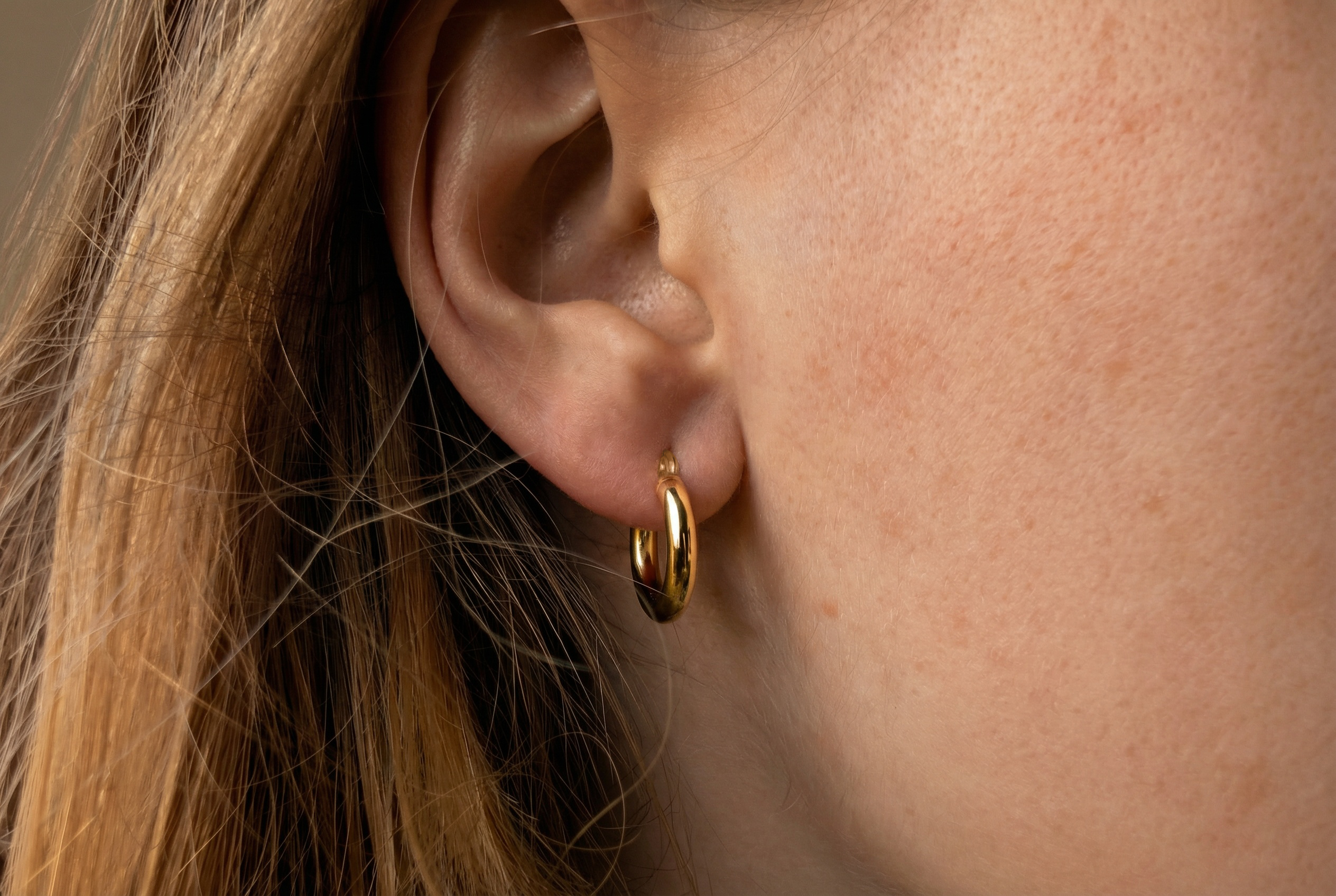 14K gold thick tube hoop earrings on model, with real gold women's jewelry