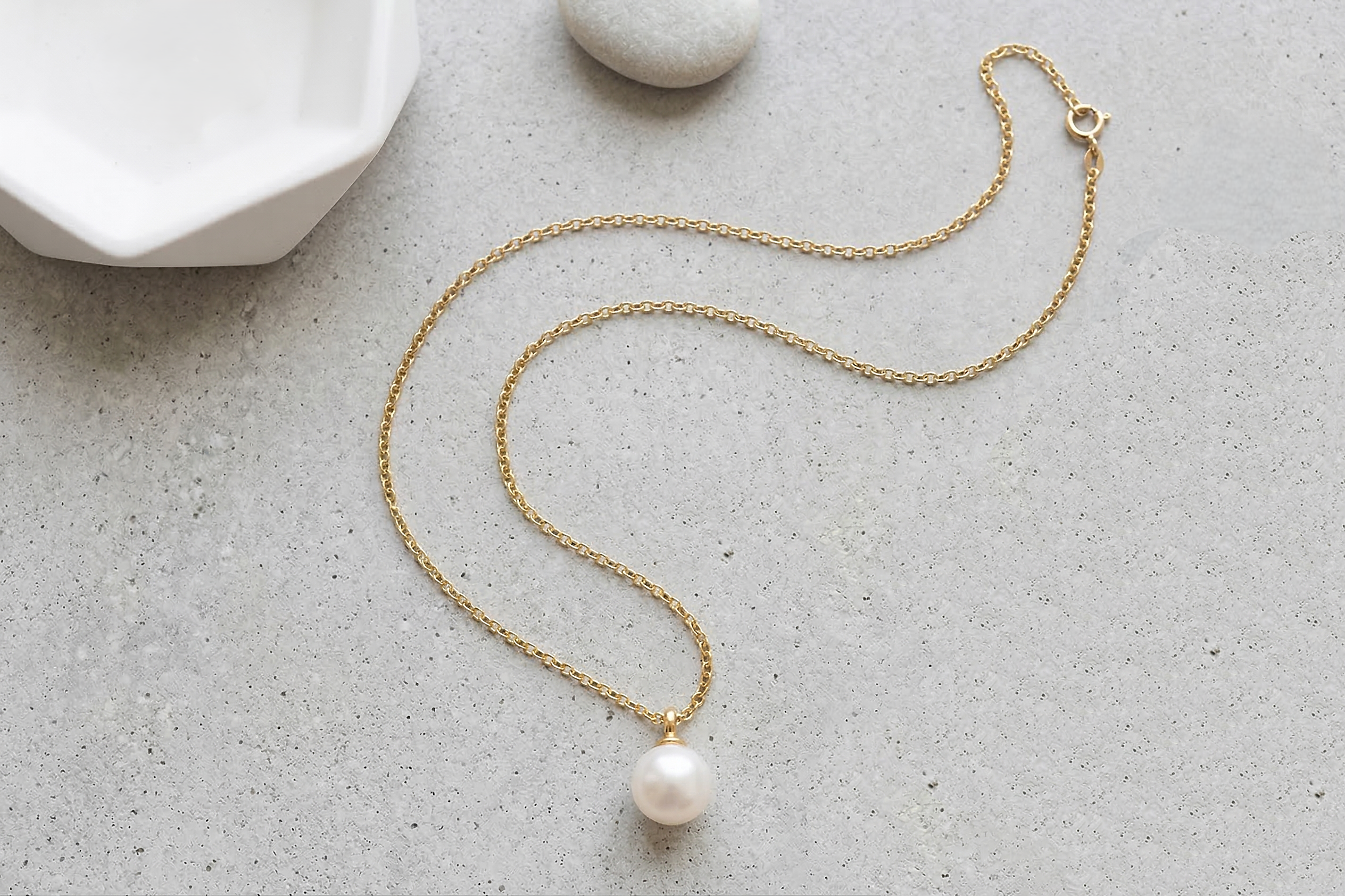 18K gold anchor chain necklace with pearl pendant on concrete – lifestyle photo