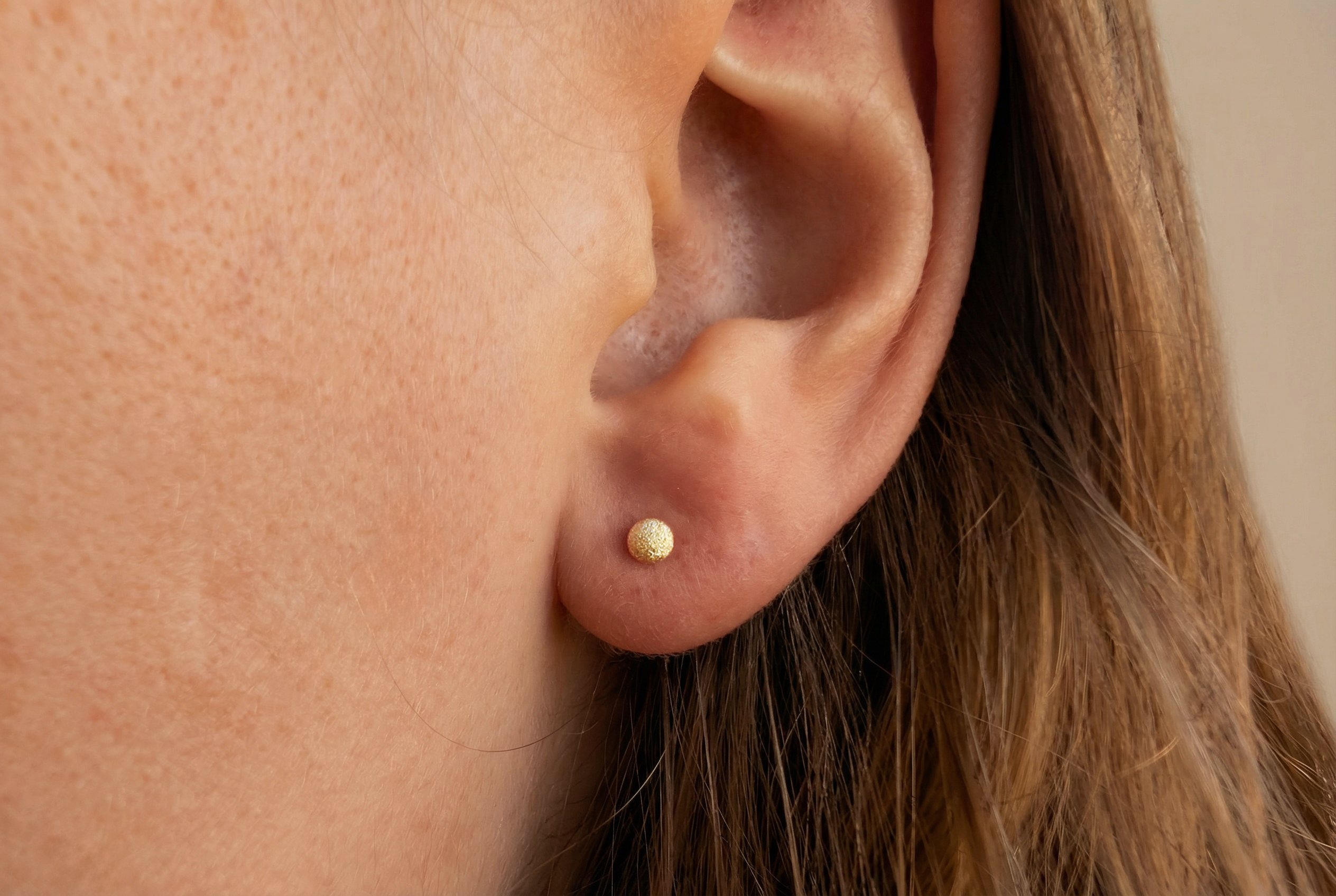18K guldörhängen med små frostade kulor studs på modell, äkta guld dam