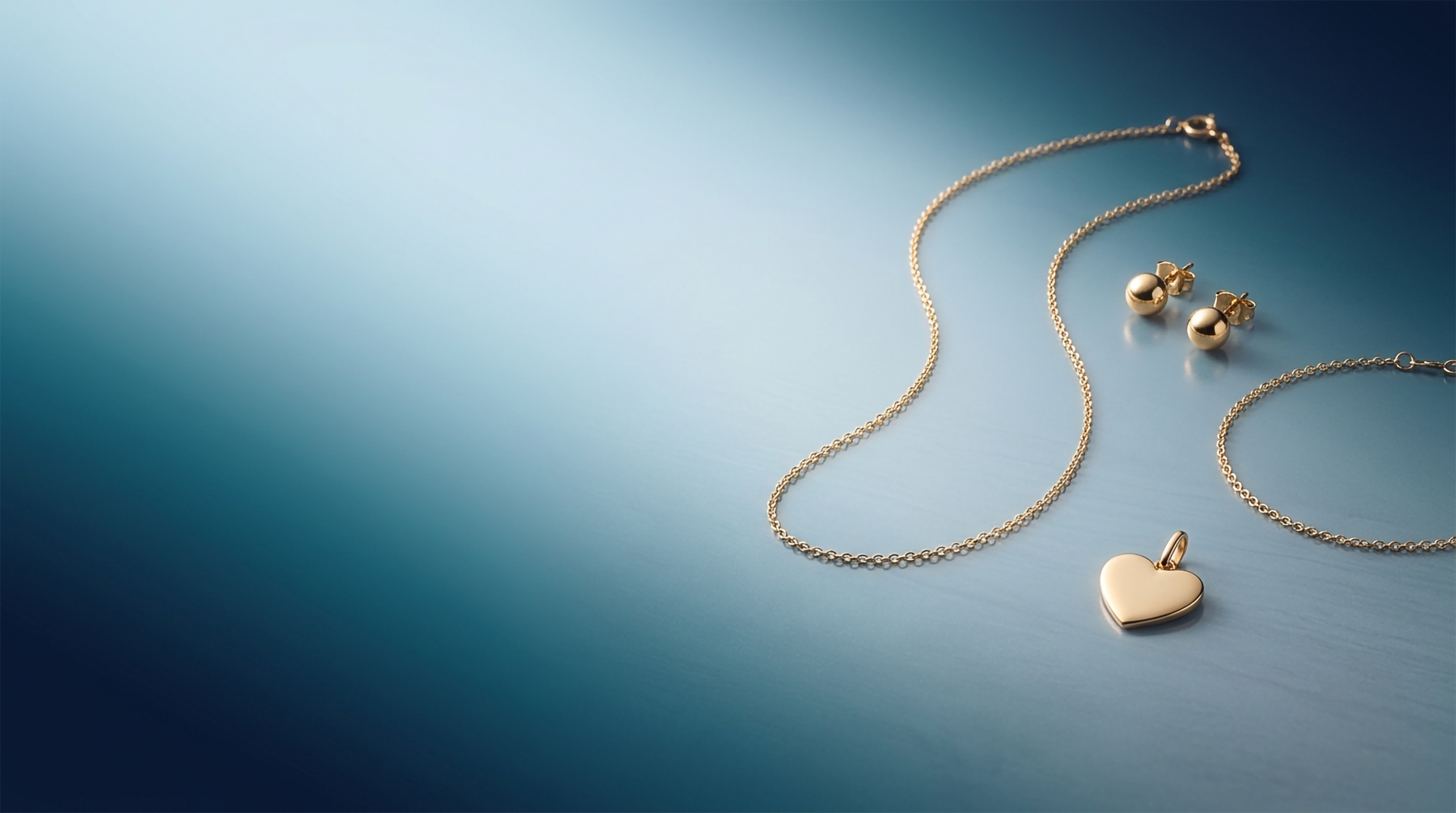 Nordic Bling gold jewellery: a gold necklace with a heart pendant, ball stud earrings and a bracelet in 18k gold.